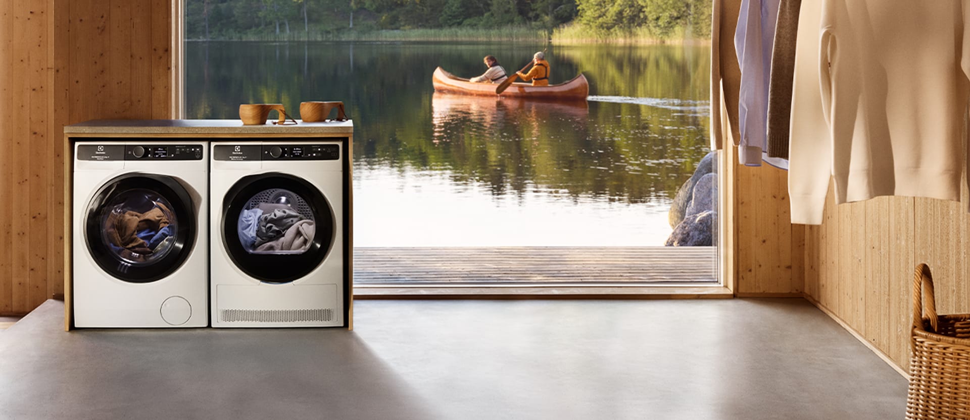 Zdjęcie pralki i suszarki na tle dużego okna, przez które widać kajak